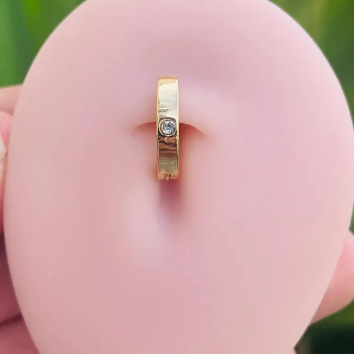 Close-up of genuine diamond bezel setting on 14K gold belly button clicker, fine body jewelry